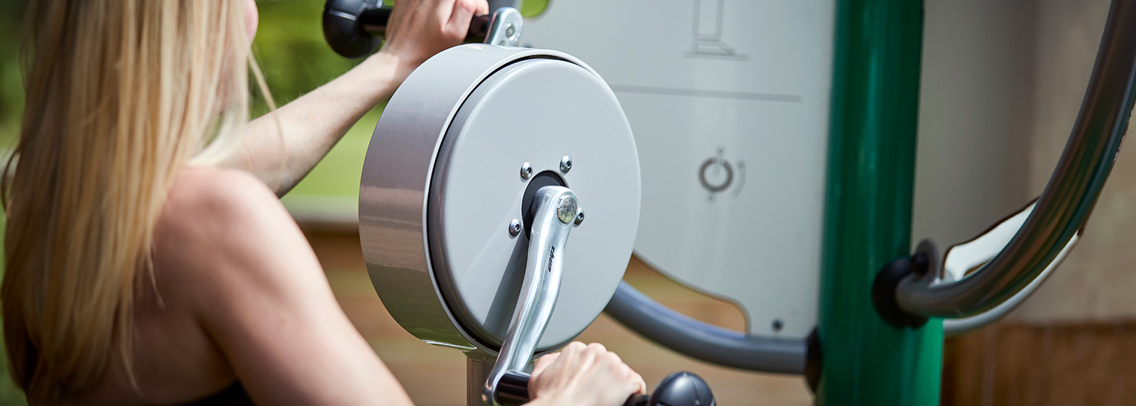 A girl exercising on an outdoor fitness machine for public use.